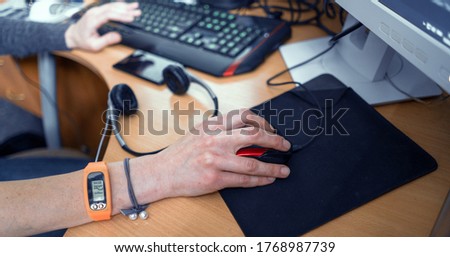 Hand Of Girl With Fitness Bracelet Working At Computer. Closeup Shot. Girl's Hands On Keyboard And Mouse At The Table. Computer Work Concept Photo.