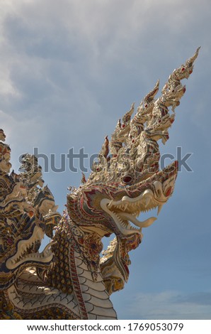 Serpent king or king of naga statue in Thai temple isolated on blue sky background.
