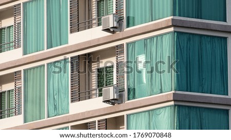 A photo of a hotel window with an air conditioner outside and a gray-green curtain.