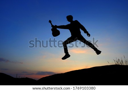 Silhouette Guitarist jump in the sunset 