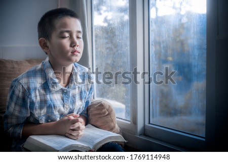 Boy praying and Seek God with the holy Bible in morning at home. Children's beliefs of christian concept.