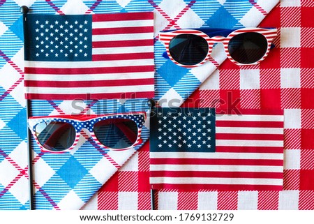 4th of July background. USA flags and sunglasses on red and blue tablecloth. Independence Day Of America, Veteran's Day, Memorial Day. Flat lay, top view, daylight. Copy space text