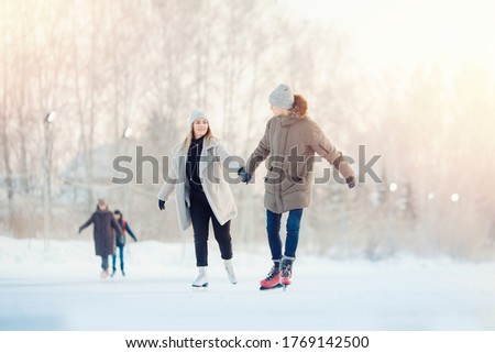 Happy young couple in sunny winter nature ice skating.
