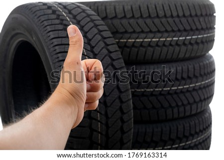 Close up picture of black new car tyre and mechanic's hand next to
