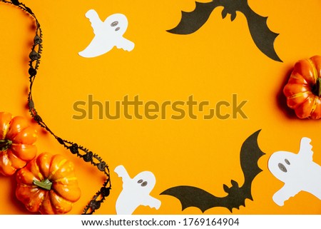 Halloween concept with pumpkins, bats, ghosts, black ribbon on orange background. Halloween banner template, flat lay, top view.