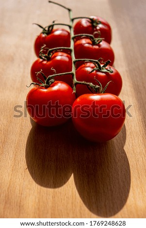 branch with a group of red tomatoes lies on an oak board. Summer season. Web banner.