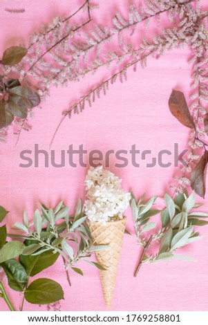 Gorgeous floral arrangement,composition of different spring flowers,leaves,stalk and white lilac in an ice cream cone on the pink paper background.Florist work place.Preparation bouqueton.Copy space