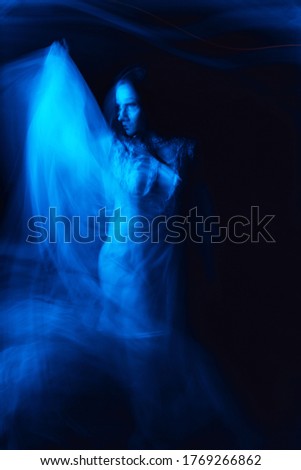 mystical silhouette of a Ghost of a witch girl in a dress on a dark background with a blur