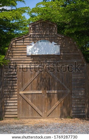 Beautiful wooden entrance barn western cowboy style and blank label with space for text and natural green tree and gravel ground countryside lifestyle concept