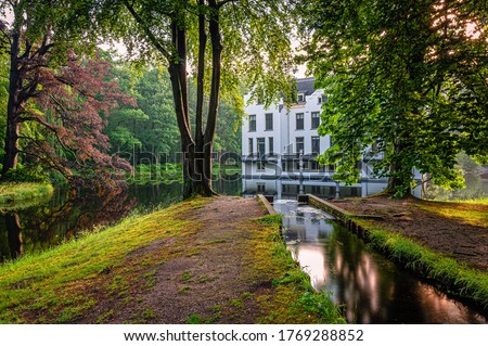 Historical Dutch white castle in Ermelo,Holland with beautiful English style garden and surrounded by a moat