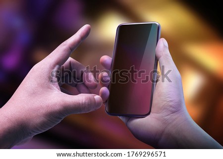 Hand holding black smartphone on dark color background. Futuristic design of digital connection technology. Creativity ideas on virtual screen concept.