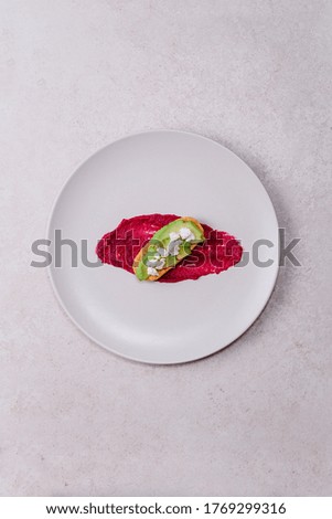 stock photography pink vegan and vegetarian beetroot hummus with pistachio in white plate accompanied by avocado bread toast and gray background
