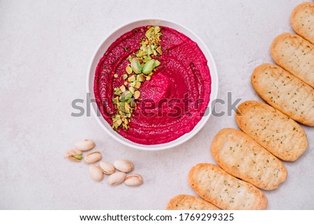 stock photography pink vegan and vegetarian beetroot hummus with pistachio in white bowl accompanied by toast bread and gray background