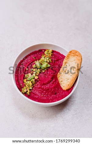 stock photography pink vegan and vegetarian beetroot hummus with pistachio in white bowl accompanied by toast bread and gray background