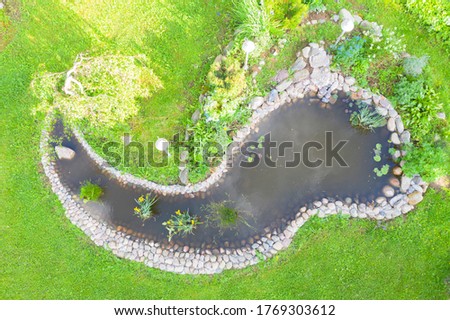 Aerial top view garden pond. Garden fish pond. Pond on natural landscape. Water garden natural pool. Exterior of a private garden. Pool with rocks