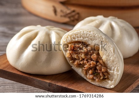 Delicious baozi, Chinese steamed meat bun is ready to eat on serving plate and steamer, close up, copy space product design concept. Royalty-Free Stock Photo #1769314286