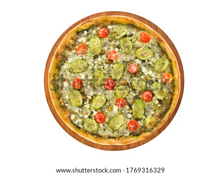 Delicious vegetarian pizza base topped with pesto and garlic, zucchini, cherry tomato, and cheese served on wooden plate and on white background.