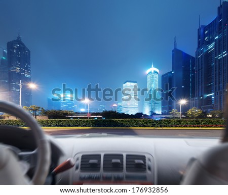 Driver's hands on a steering wheel of a car and night scene