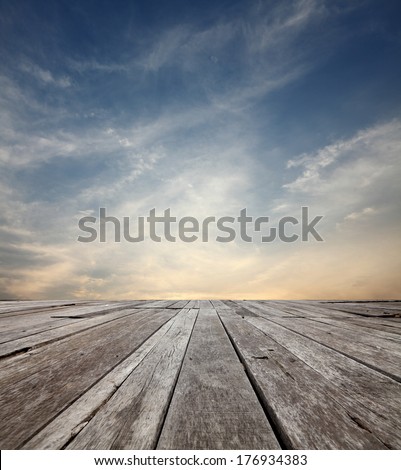 Surreal cloudy evening sky in the horizon of an empty grungy timber deck platform. 
