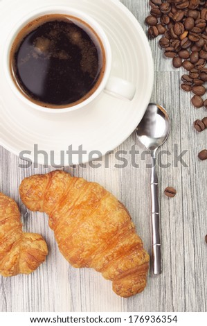 A cup of black coffee and two croissants