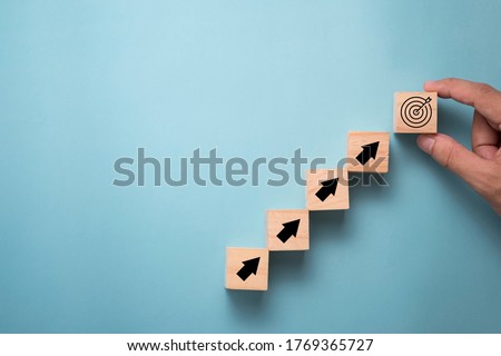 Hand putting virtual target board and arrow which print screen on wooden cube. Business achievement goal and objective target concept. Royalty-Free Stock Photo #1769365727