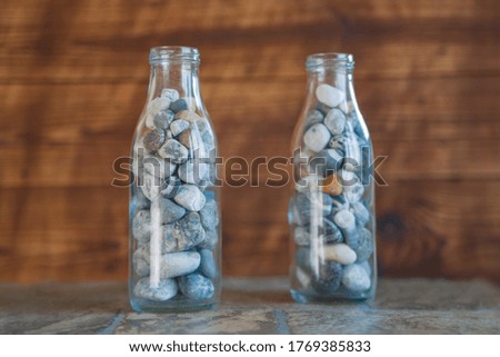 Sea pebbles in a vintage bottle. Keeping summer vacation memories concept. 