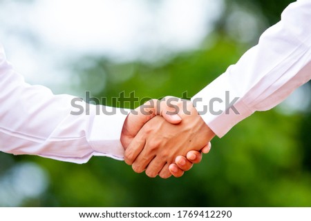 A male close up holding a hand between two colleagues who have a good relationship concept in a natural background