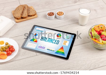 Organic food and tablet pc showing BALANCED inscription, healthy nutrition composition
