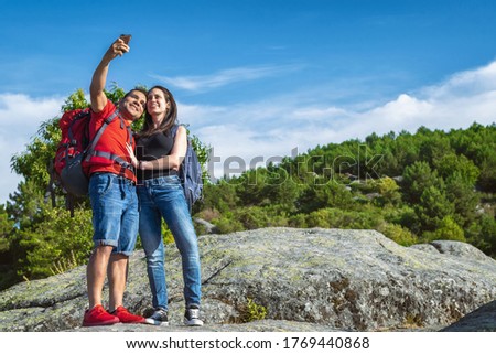 Couple of hikers in the mountains taking a photo with their mobile