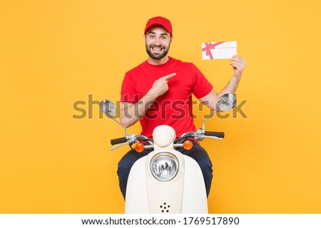 Delivery man in red cap t-shirt uniform driving moped motorbike scooter hold certificate isolated on yellow background studio Guy employee working courier Service quarantine pandemic covid-19 concept.