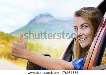 Happy driver woman shows thumb up against mountains background. Car insurance concept 