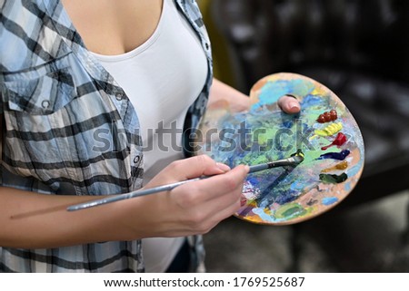 The artist selects a color on the palette. Close-up, no face