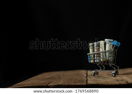 Money in a cart milking products. Shopping online. Dollars on a black background