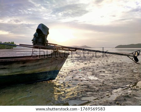 Picture of a long-tail boat with the sun set near the horizon.