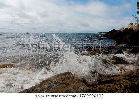 A splash of seawater on a rocky shore at daytime Royalty-Free Stock Photo #1769596103