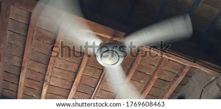 A ceiling fan blowing fast under the roof