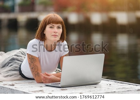 Beautiful concentrated young female student using modern laptop outdoor