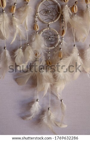 Closeup of white dream catcher a small white hoop decorated with feathers and beads.