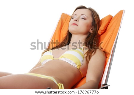 Young woman lying on orange sunbed isolated over white background 