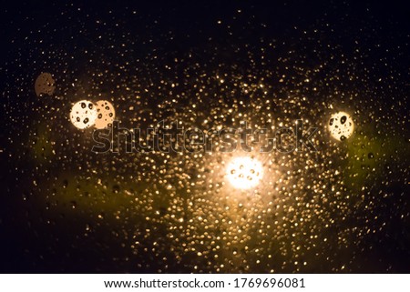 Drops of rain on window glass, lanterns in the background -image
