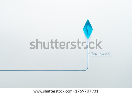 Blue paper ship in new direction on white background, New normal concept, copy space