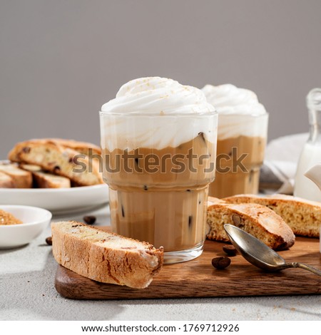 Iced coffee latte with whipped cream and biscotti cookies in glass.