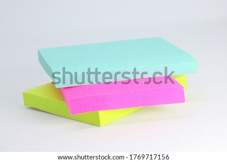 Small note paper consisting of purple, blue and yellow color square style and placed on a white background