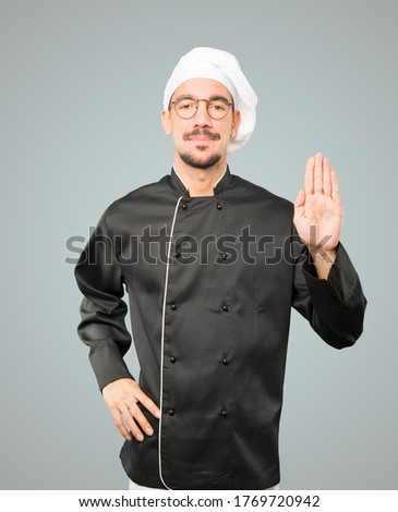 Happy young chef making a gesture of stop with his palm