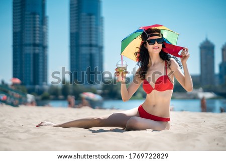 young female sitting on urban beach in medical mask and drinkg mojito cocktail