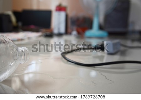 the water overturn from plastic  bottle with  plug power cord plugged in In the area there is water in the house, a sign of danger to life on blurred Electrical appliances background