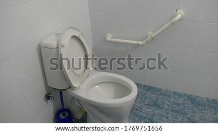 toilet in the toilet with a handrail for the disabled