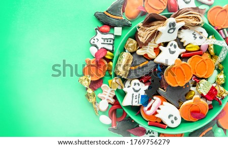 Halloween Jack o Lantern candy bowl with candy and halloween cookies Trick or Treat on green background
