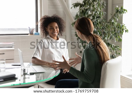 Happy diverse millennial women distracted from computer work chat talk in office during break, smiling young multiracial female colleagues have fun brainstorm discussing ideas or thoughts at workplace Royalty-Free Stock Photo #1769759708