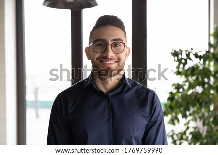 Close up headshot portrait of smiling young Arabic businessman in glasses pose at workplace, profile picture of millennial confident Arabian male employee in spectacles show leadership and motivation Royalty-Free Stock Photo #1769759990